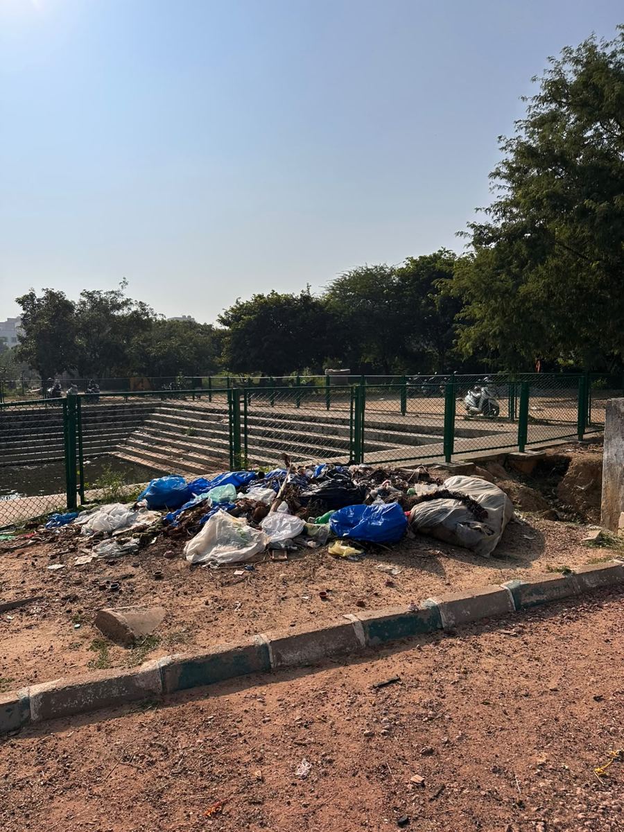 An open garbage dump of plastic sacks and bags on the ground beside the kalyani fence.